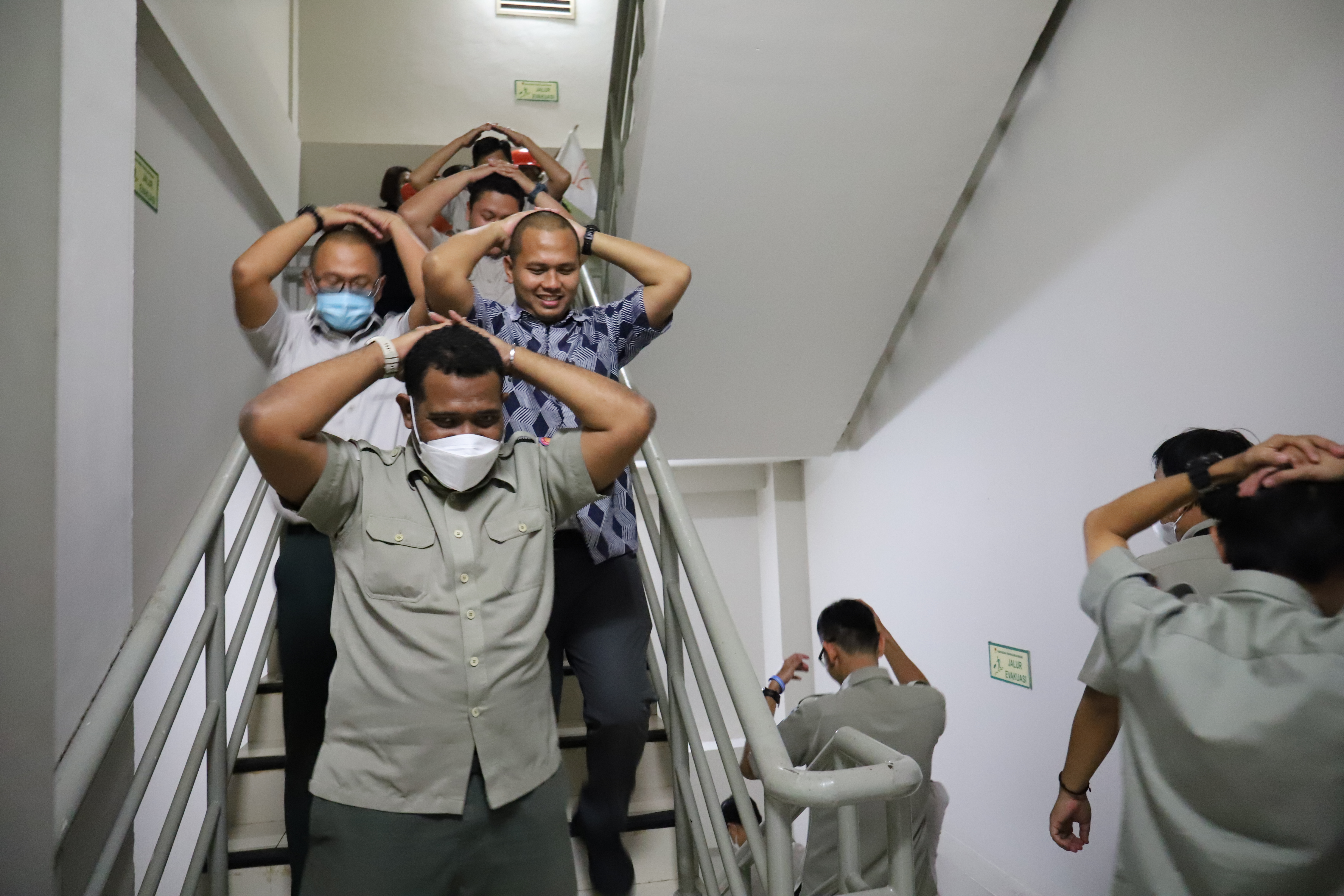 Para pegawai sedang melakukan evakuasi mandiri menuju titik kumpul, saat simulasi evakuasi bencana gempa di Gedung Graha BNPB, Jakarta pada Rabu (26/4).